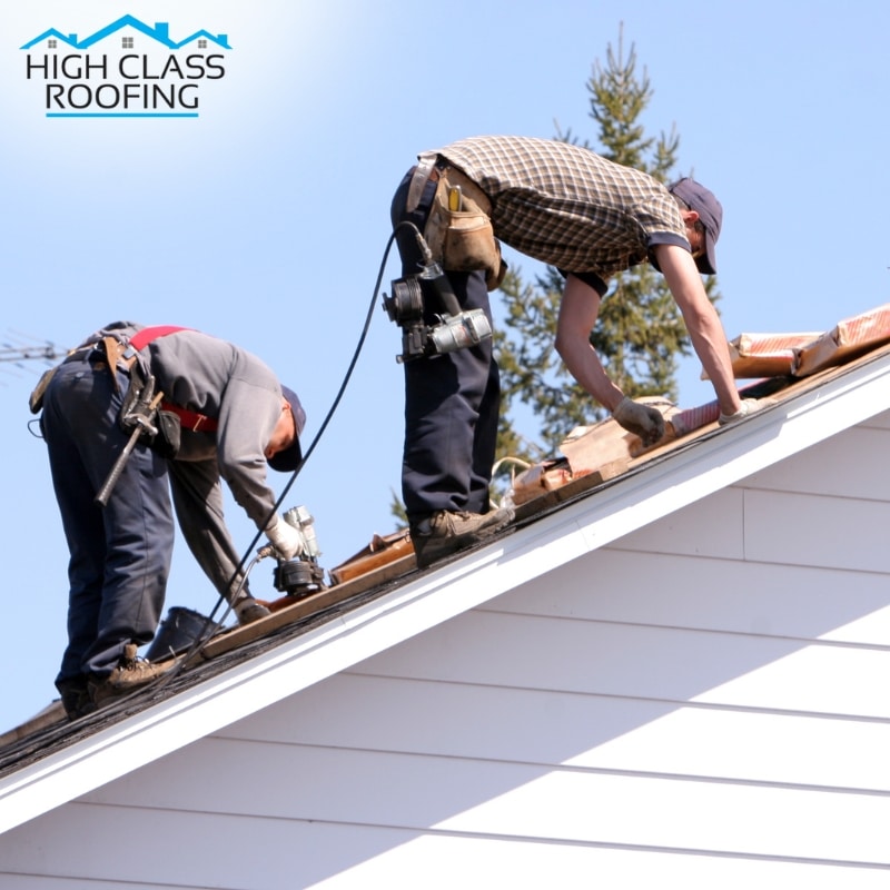 Two roofers in safety gear doing roof restoration in Sydney