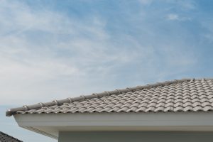 Close-up view of a white tile roof with a clear blue sky in the background. This image can be used for content about restoring roof tiles.